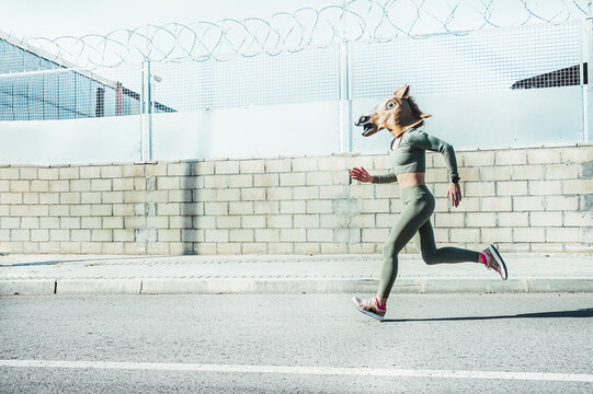 Mature woman in horse mask running on road