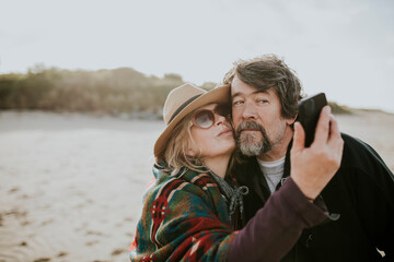 Happy retired couple take a selfie by the beach