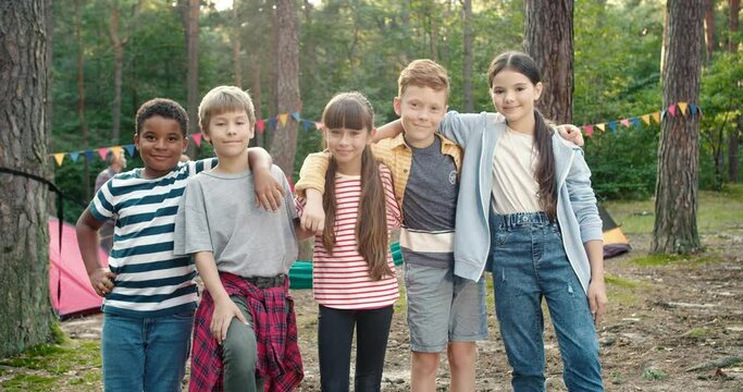 So happy. Portrait of the cute children embracing at the forest while spending time at the camping at the nature. Happy childhood concept