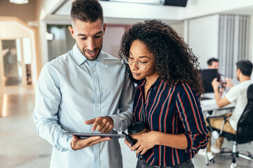 Business people working with digital tablet while discussing together in a coworking place.