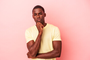 Young African American man isolated on pink background thinking and looking up, being reflective, contemplating, having a fantasy.
