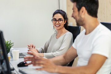 Successful business team working together with computer while talking in coworking place.