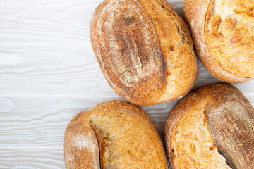 Artisan wheat bread lies on the wood surface, background, top view.