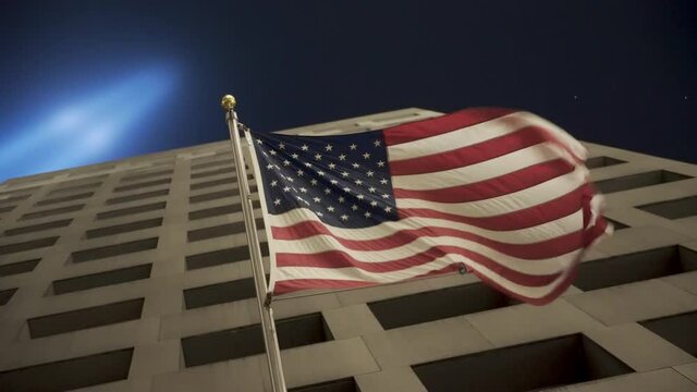 American Flag Waving In NYC With September 11th Memorial Lights Shining Above