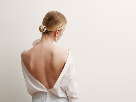 Minimalist photo, Fashionable girl in stylish summer things - white shirt. View from the back. Earrings, a ring . Street fashion , blogger style . Beauty . Minimalist Fashion clothes