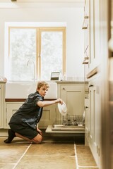 Fototapeta na wymiar Boy loading dishwasher, basic house chores