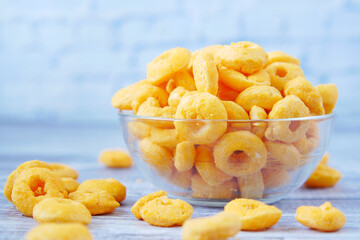 puffed corn rings chips in black bowl on white background