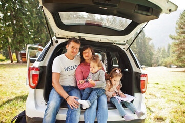 Family with two baby girls at vehicle interior. Children in trunk. Traveling by car in the mountains, atmosphere concept.