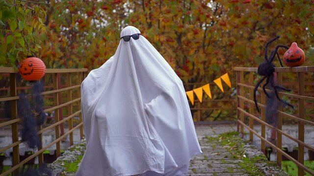 crazy fun ghost halloween. man in white sheet runs in street. Fancy dress flies. Funny witch dance. concept of holiday in carnival costume in fall. Orange pumpkin and spider. casting in glasses. 