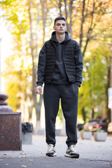 Fashionable man in grey costume and vest standing in the autumn city sidewalk