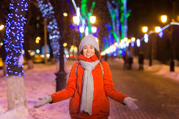 Winter holiday season. Christmas, New Year concept. Funny happy woman spend time having fun near illuminated and decorated showcase on city street.