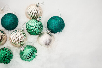 beautiful green and gold Christmas toy in the shape of a ball on white snow. Christmas pattern from the decor, top view, copy space