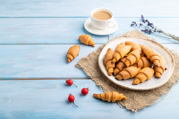 Homemade bagel roll with cup of coffee on a blue wooden background. side view, copy space.