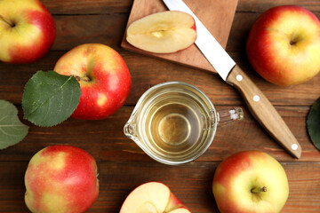 Natural apple vinegar and fresh fruits on wooden table, flat lay
