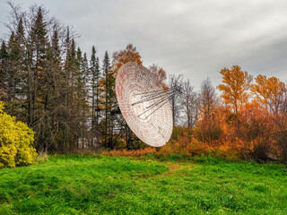 Vintage Radio Telescope, a large satellite dish on a background of observation forest and cloudy...