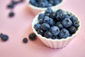 Flat lay of fresh organic juicy blueberries in a bowl on pink background, top view, copy space. Concept of healthy and dieting eating , antioxidant, vitamin, summer food.