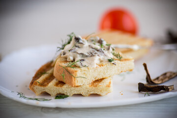 fried bread toast with cheese spread with boiled dried mushrooms on a wooden table.