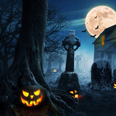 Halloween pumpkins near a tree in a cemetery with a scary house. Halloween background at night...
