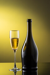 tall champagne glass next to bottle with highlights on yellow background