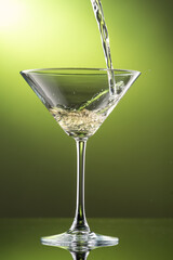 pouring martini into a glass on a green background
