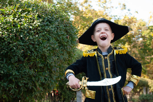 A Boy In A Pirate Costume For Halloween With Space For Text. A Child With A Saber In His Hands Sweets Or Life At A Party