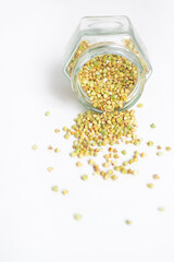 Green dry buckwheat spilled out of a glass jar, clean vegetarian food, organic food, zero waste,...
