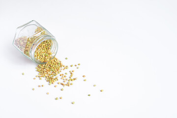 Green dry buckwheat spilled out of a glass jar, clean vegetarian food, organic food, zero waste,...