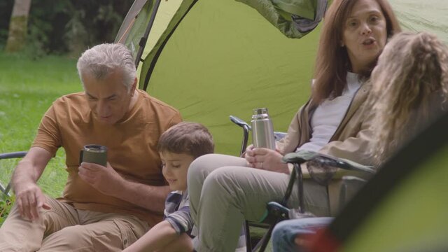 Handheld Shot of Grandparents and Grandchildren Sitting by Tents
