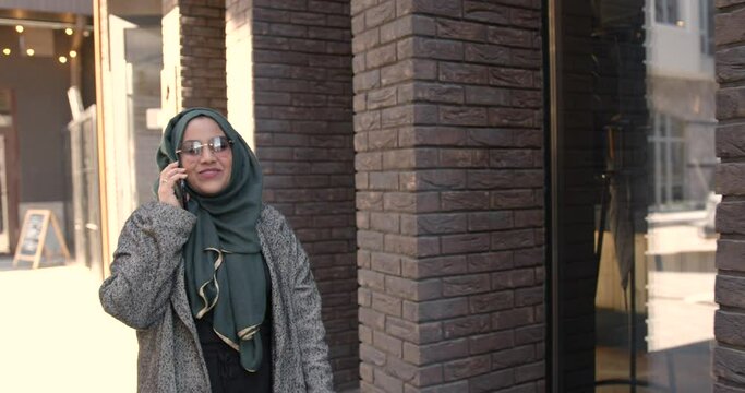 Muslim woman in veil talking by phone outdoors