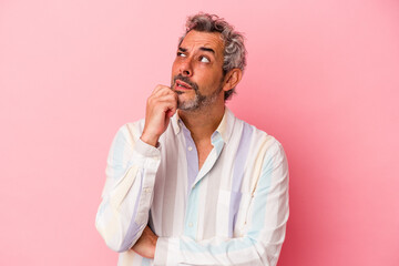 Middle age caucasian man isolated on pink background  looking sideways with doubtful and skeptical expression.