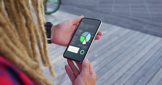 Hands of caucasian man with dreadlocks using smartphone with statistics on screen
