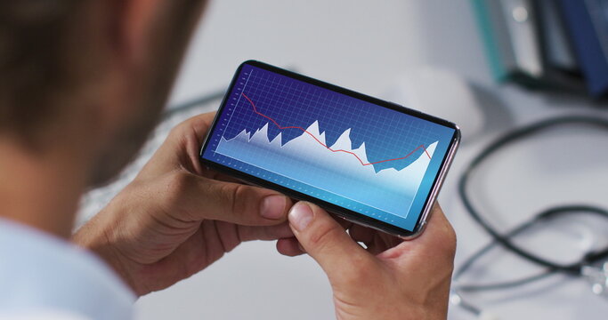 Hands of caucasian man using smartphone with statistics on screen