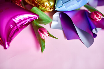 Flat lay style of color balloons with tulips floral decoration on pink background.