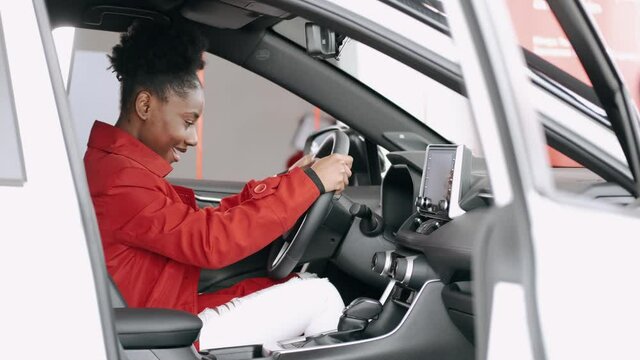 African american woman choosing a car in a salon and checking the salon