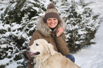 Beautiful girl playing with her dog in the snow. Golden Retriever