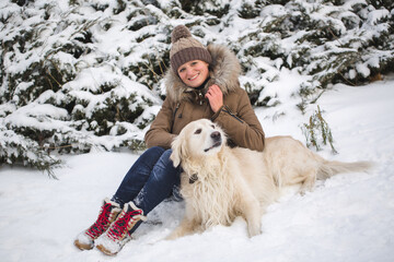 Beautiful girl playing with her dog in the snow. Golden Retriever
