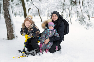 Father and children: son and daughter sledding in a snowy forest.