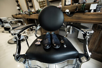 Shoes, watch, tie on the chair. The groom is going to the barbershop in the morning