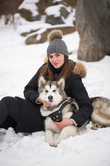 Beautiful girl in winter forest with dog. Play with the dog Siberian husky.