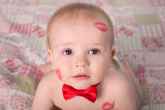 Image of adorable child with red kisses on the skin, happy boy, sitting in the Studio on the bed, angel, romantic holiday, Valentine's Day.
