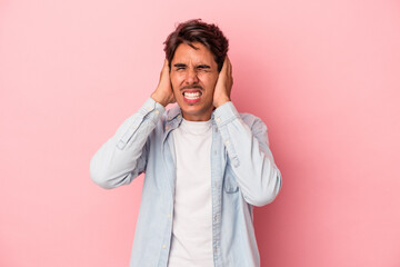 Young mixed race man isolated on white background covering ears with hands.