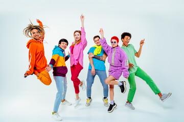 Smiling young male and female friends dancing against white background