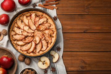 Delicious apple pie and ingredients on wooden table, flat lay. Space for text