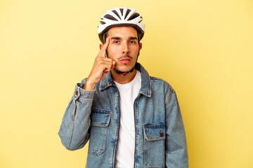 Young mixed race man wearing a helmet bike isolated on yellow background pointing temple with finger, thinking, focused on a task.