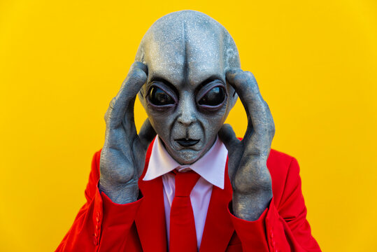 Portrait of man wearing alien costume and bright red suit looking toward camera