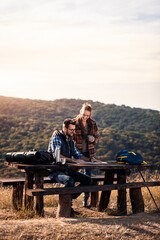 Couple resting after hiking looking for new direction on map.