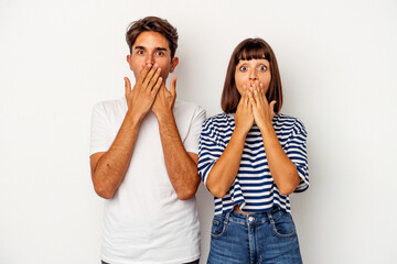Young mixed race couple isolated on white background shocked, covering mouth with hands, anxious to discover something new.