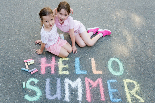 Hello Summer Concept. Cute Children Girls Hugging Near Multicolored Inscription On Pavement On Sunny Day.  Sidewalk Chalk Games For Kids