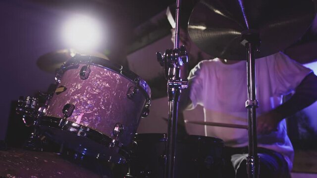 Male Artist hits the drum kit, snare drum and crash. Night show in a musical instrument recording studio. The drummer on the Repetition of rock or metal music band. Musical party. Slow motion
