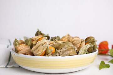 Ripe physalis fruits with dry husk on white table. Space for text